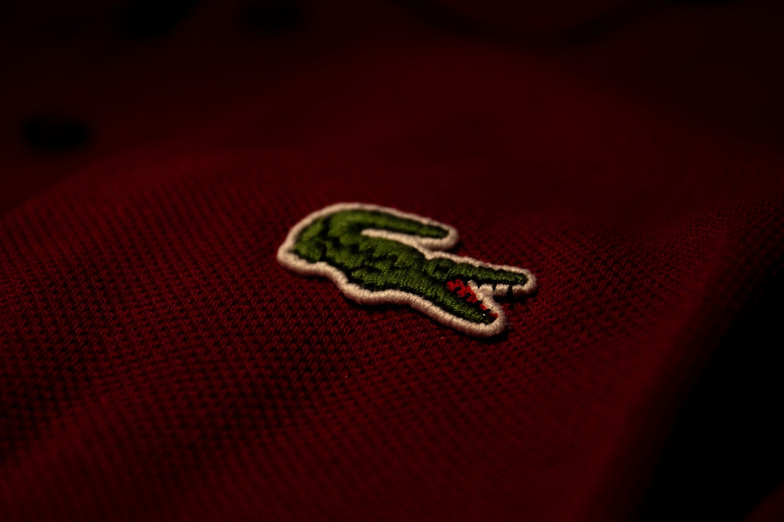 a close up of a red polo shirt with a green alligator embroidered on it