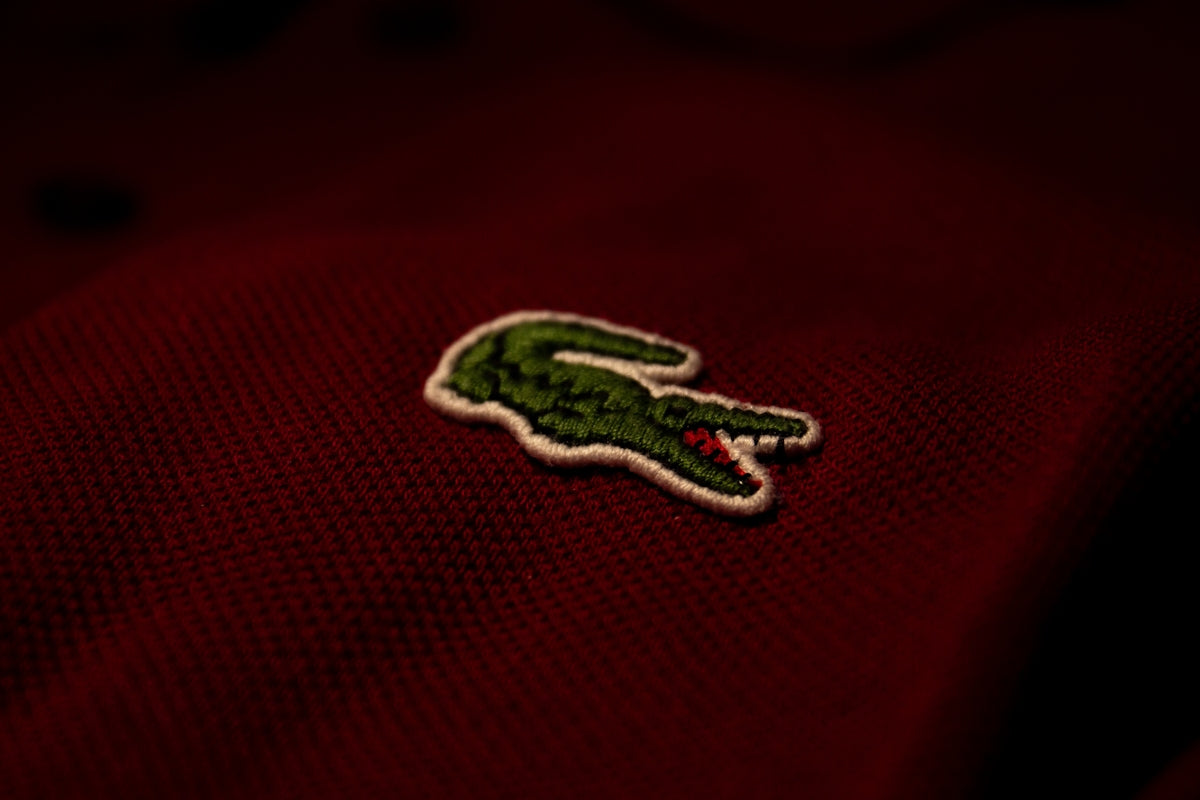 a close up of a red polo shirt with a green alligator embroidered on it