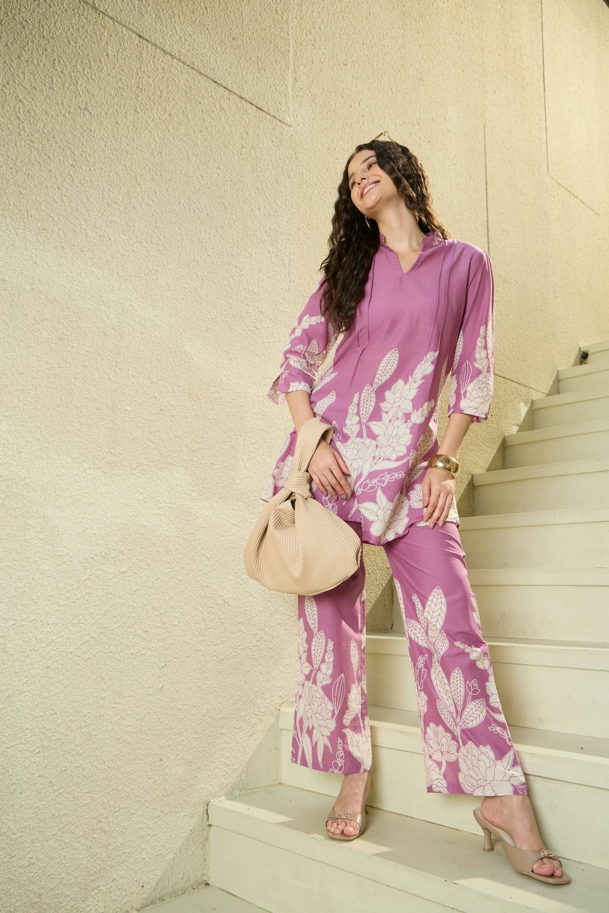 Woman in floral purple outfit on stairs with purse