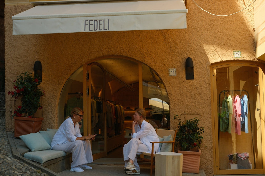 Two women in white outfits sit outside a store.