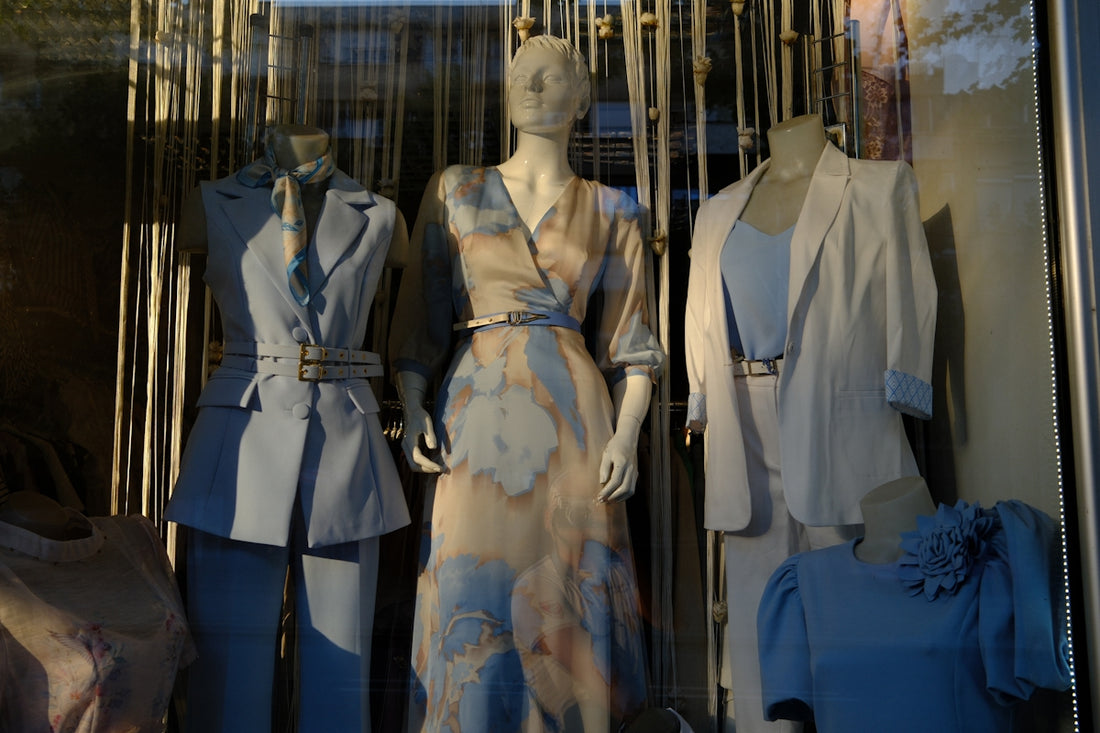 Mannequins displaying fashionable clothing in a shop window.