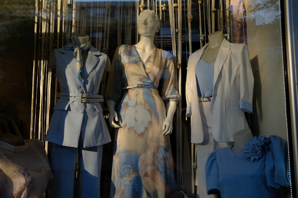 Mannequins displaying fashionable clothing in a shop window.